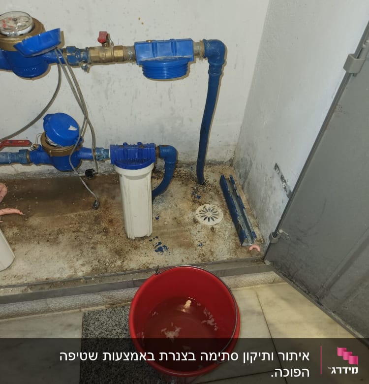 דליפה בצנרת עם דלי אדום לאיסוף מים